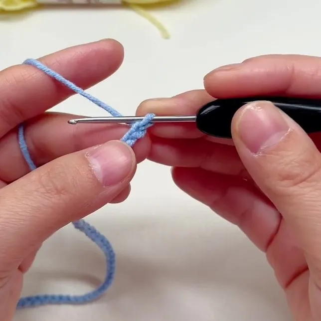 48-Chain Foundation for the Mini Scarf Crochet hook making a foundation chain with light blue yarn for a beginner project