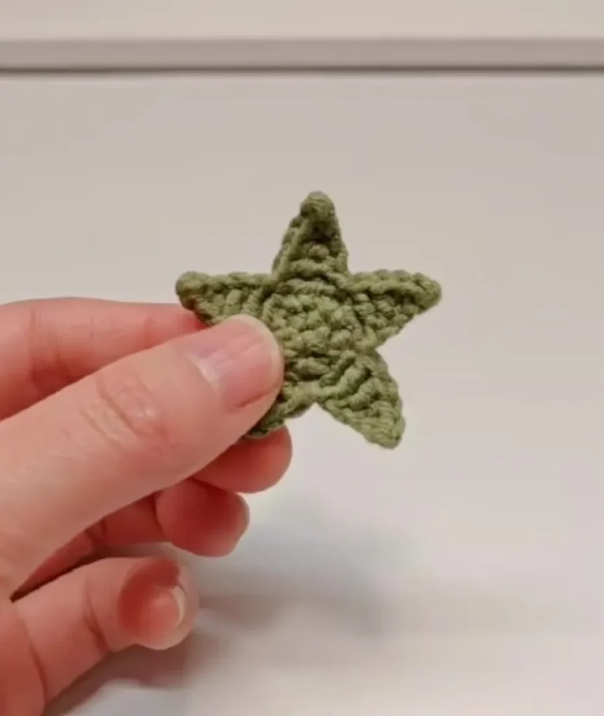 Mini Crochet Strawberry Keychain (Easy Beginner Pattern) 2 Finished crochet strawberry leaf piece showing five pointed star shape worked in green yarn