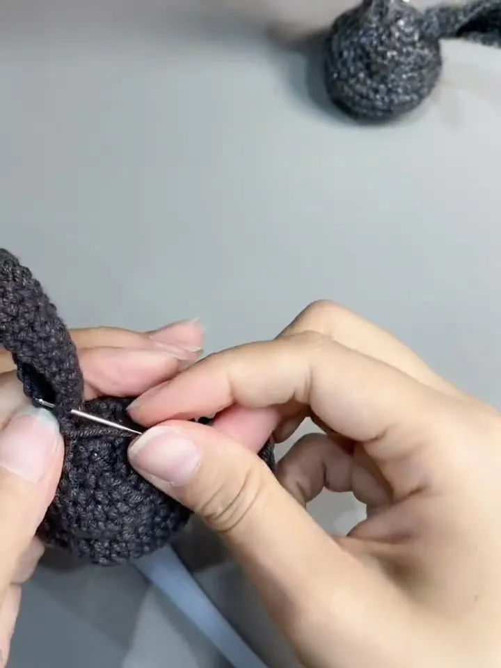 sewing a crochet bunny ear onto the head with a yarn needle