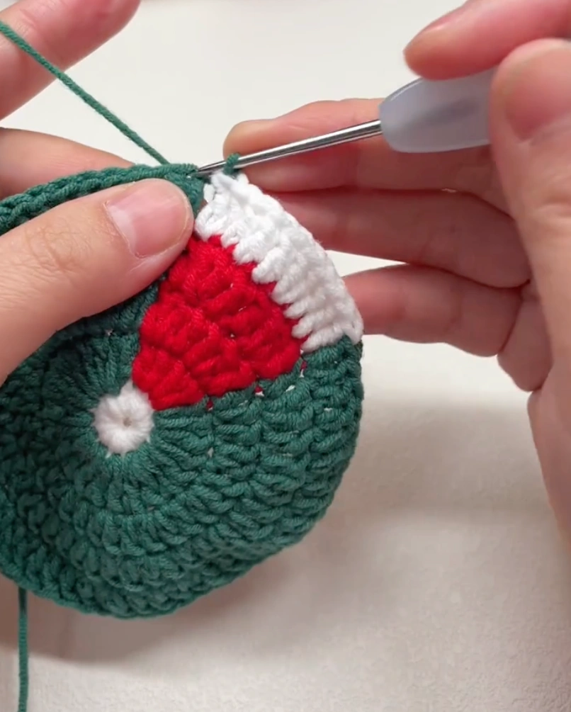 Santa Hat Crochet Coaster: A Festive Beginner Christmas Pattern 5 White yarn brim being added to the red Santa hat section of a crochet coaster