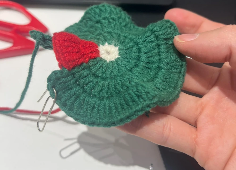Santa Hat Crochet Coaster: A Festive Beginner Christmas Pattern 8 Christmas crochet coaster curling upward slightly while being held before blocking
