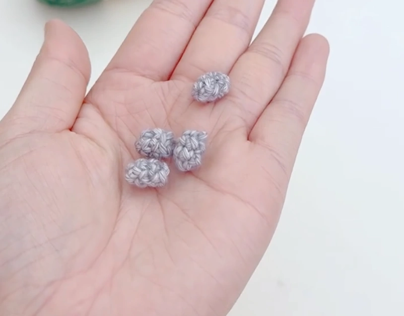 Mini Crochet Turtle Pattern for Beginners: Tiny Amigurumi Turtle 4 Five small gray crochet pieces for the turtle legs and tail resting in a hand