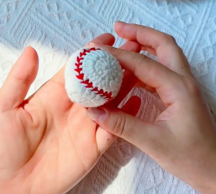 Finished mini crochet baseball with white panels and red joining seam