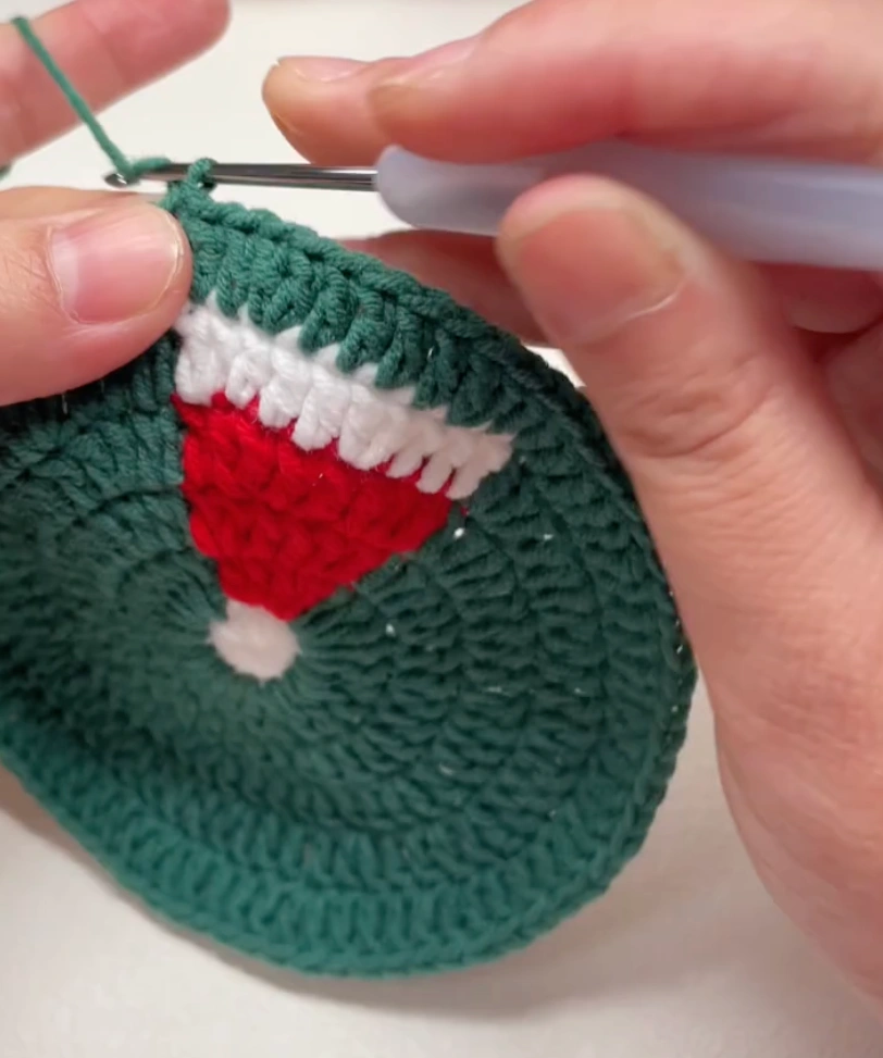 Santa Hat Crochet Coaster: A Festive Beginner Christmas Pattern 6 Green double crochet round worked around the red and white Santa hat design in a crochet coaster