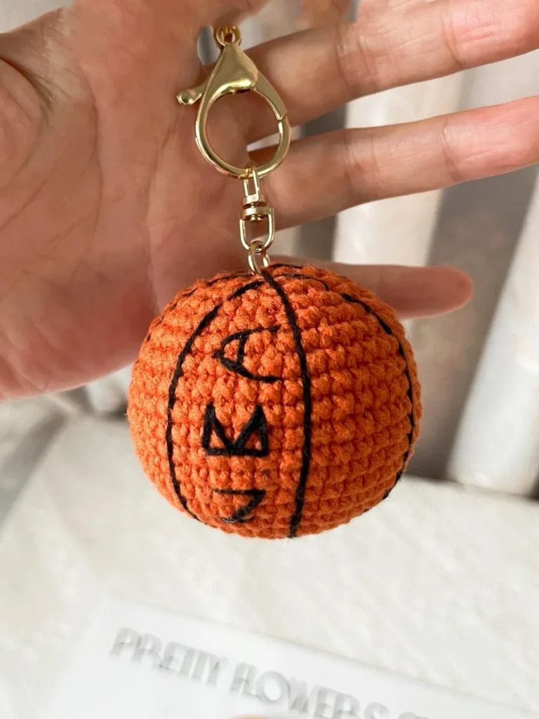 Finished mini crochet basketball keychain with black embroidered lines and gold clasp