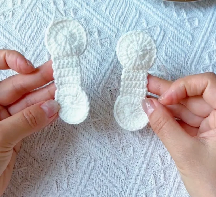 Two white crochet baseball panels before joining with red yarn